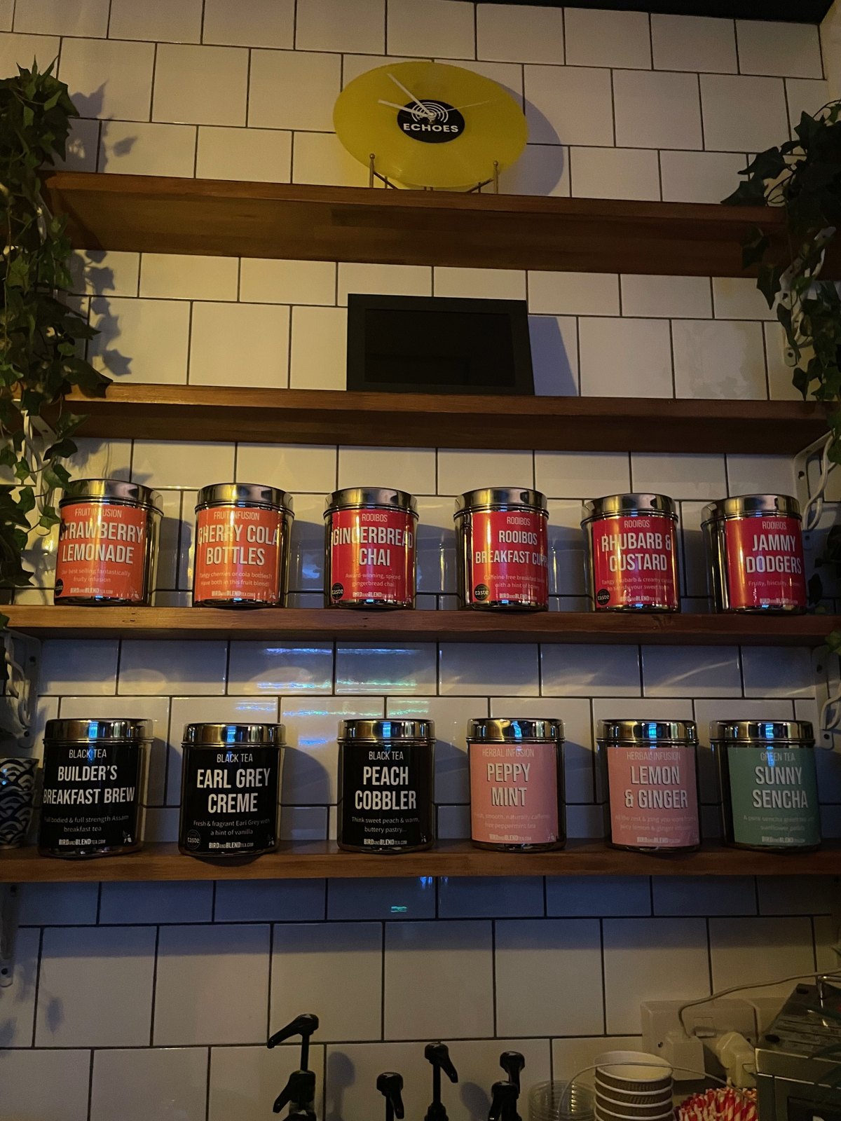 Shelves of loose-leaf tea tins beneath a yellow vinyl record